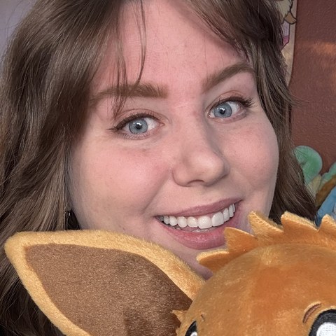 Bry smiling beside her Eevee plush